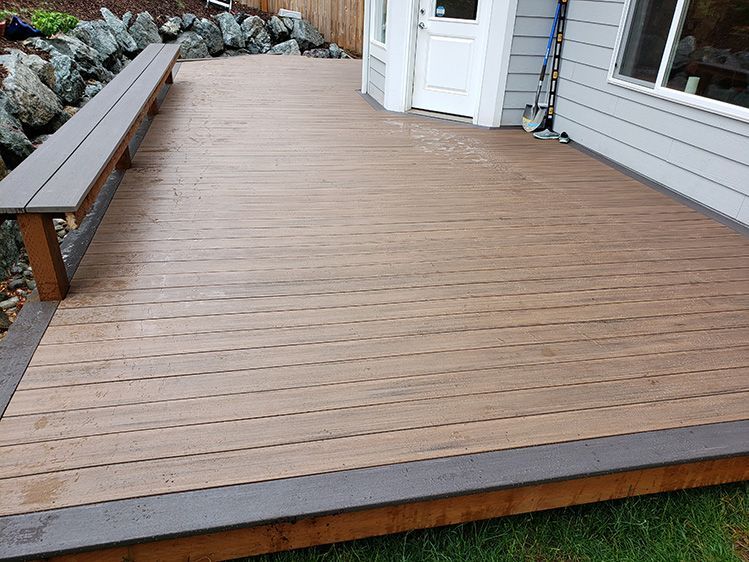 A wooden deck with a bench in front of a house.
