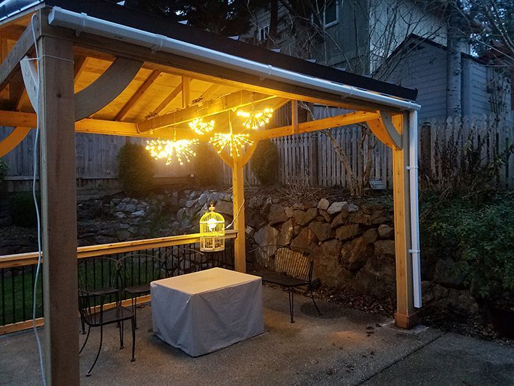 A gazebo with a table and chairs underneath it is lit up at night.
