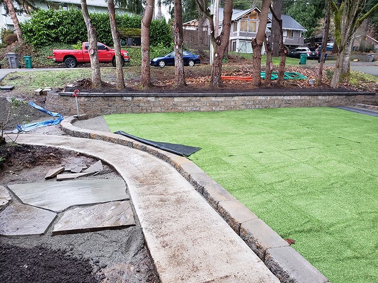 A concrete walkway is being built around a lush green lawn.
