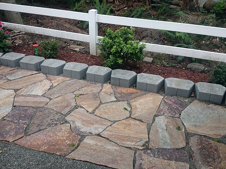 A stone walkway with a white fence in the background