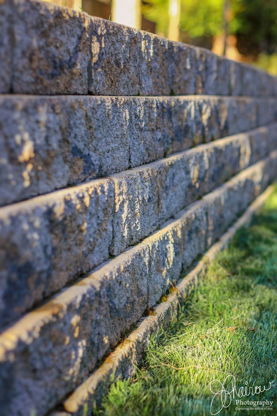 A brick wall is sitting on top of a lush green lawn.