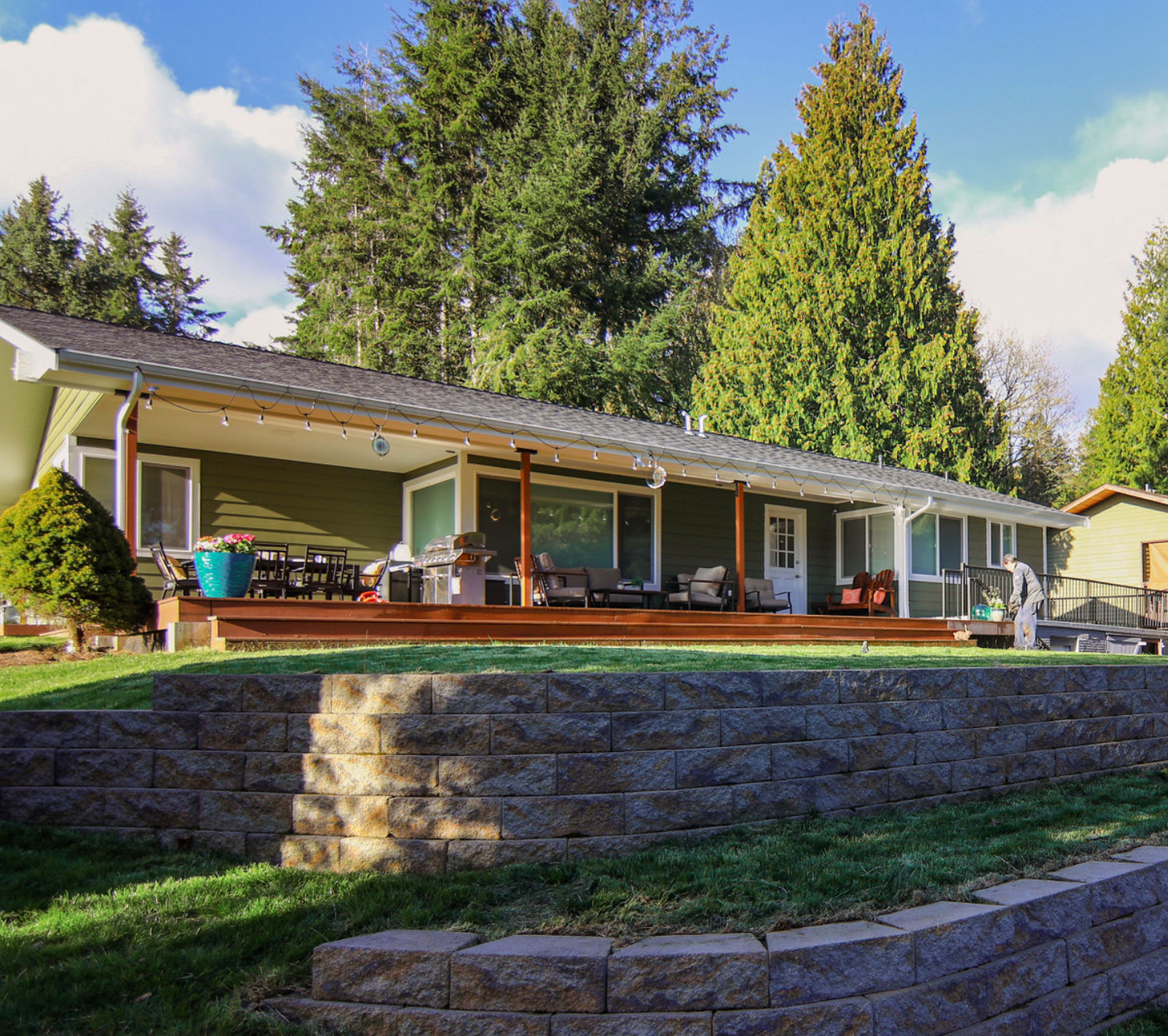 A house with a large porch and a brick wall in front of it