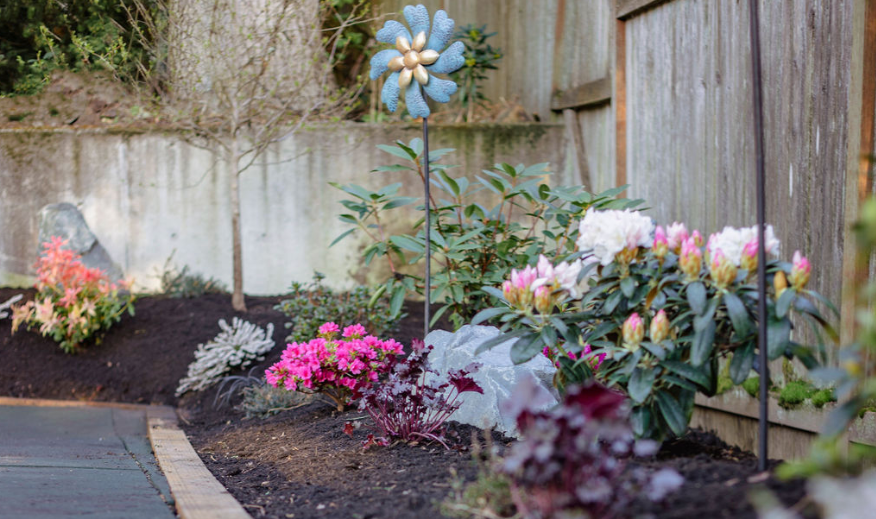 A garden with flowers and a windmill in the middle of it.