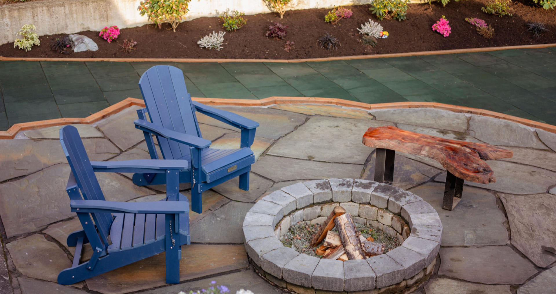 Two blue chairs are sitting next to a fire pit on a patio.