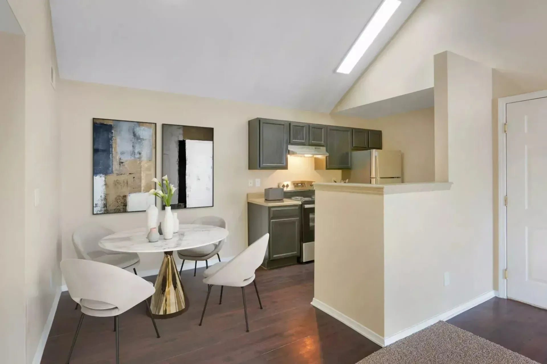 Dining area and kitchen with dark cabinets, stainless steel appliances, and vaulted ceiling.