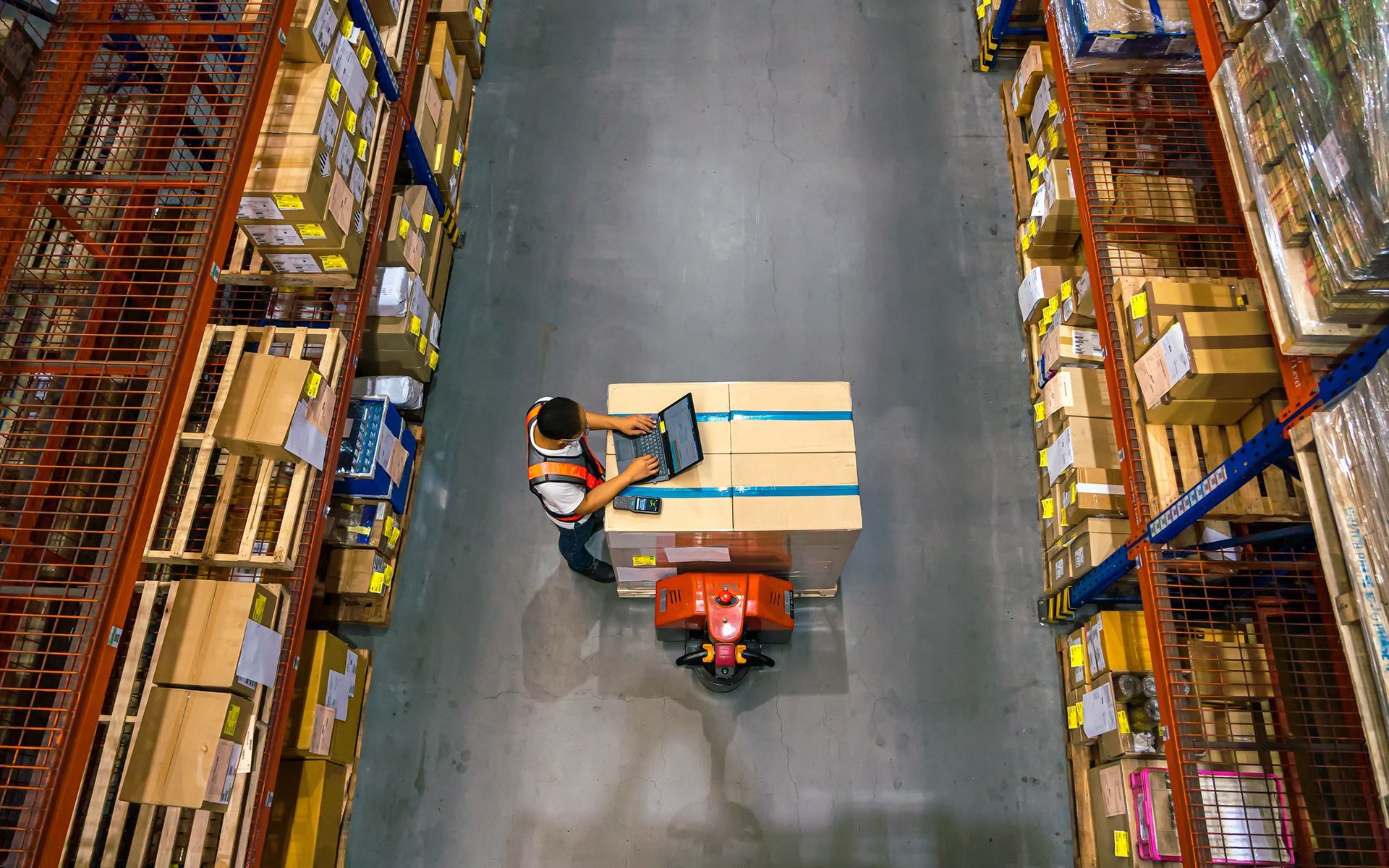 A man is sitting on a pallet in a warehouse.