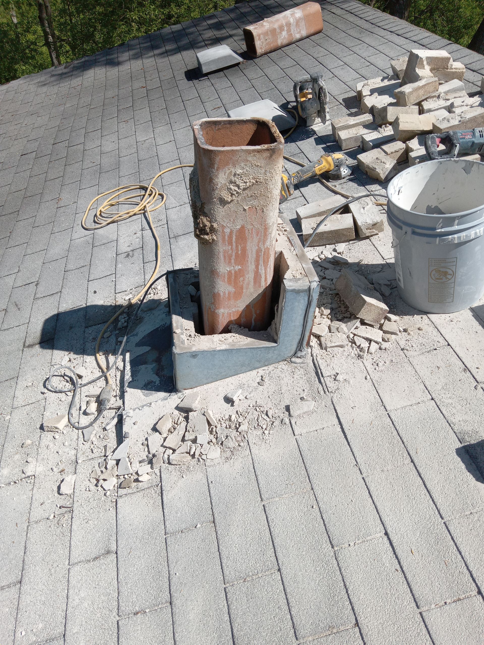 Rooftop with a partially dismantled brick chimney and construction debris.