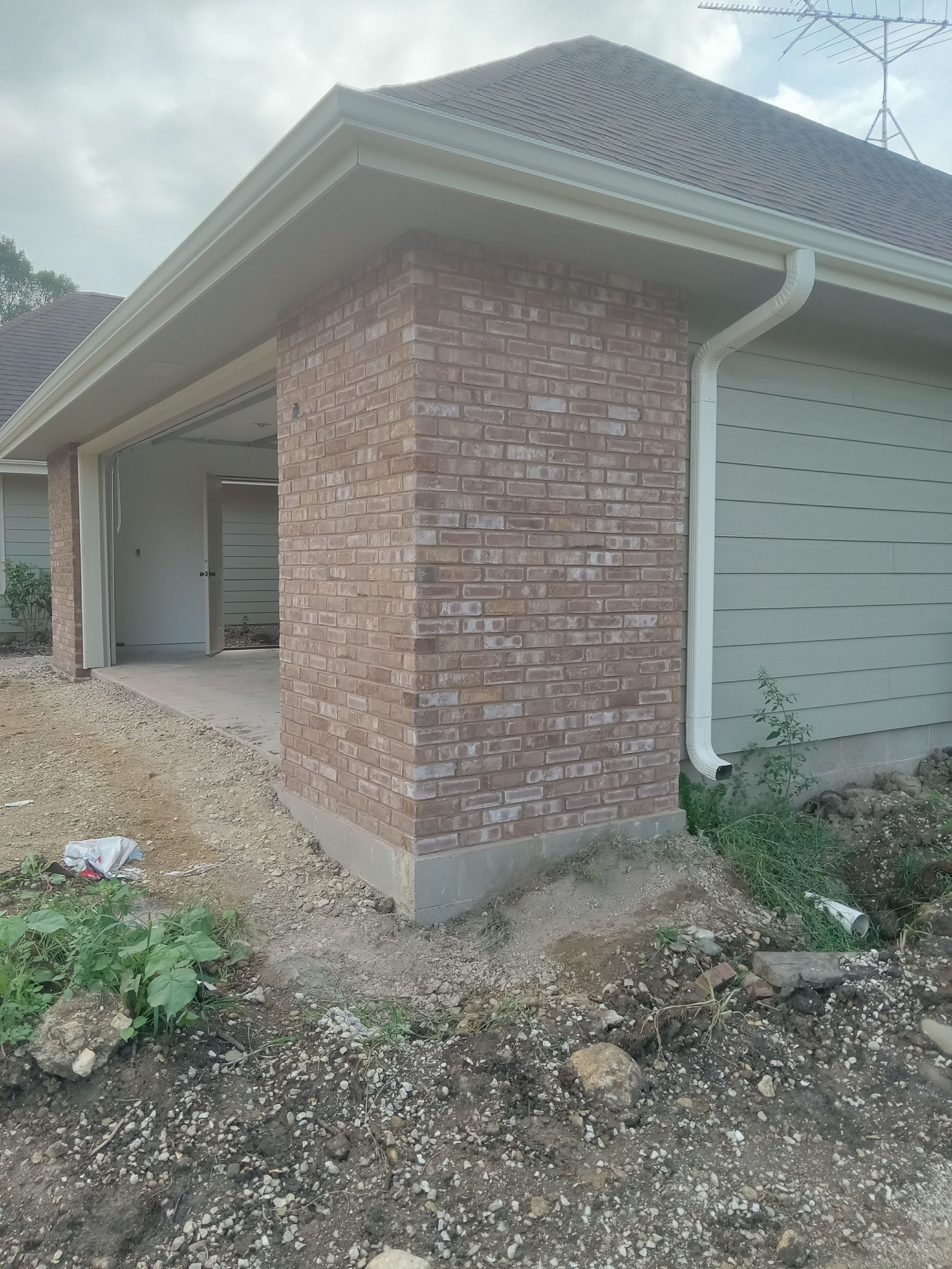 Garage exterior with brick facade and light green garage door, under construction.