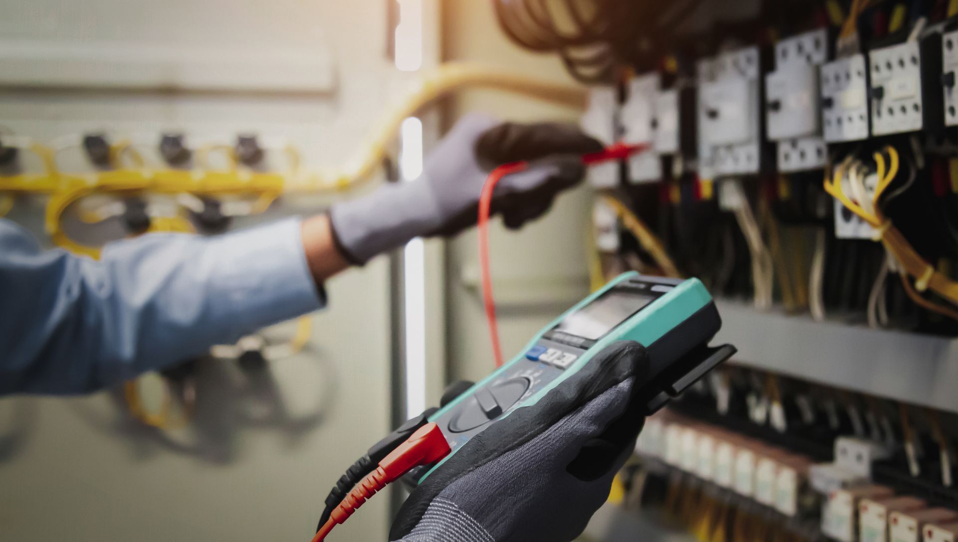 An electrician is using a multimeter to test a circuit board.