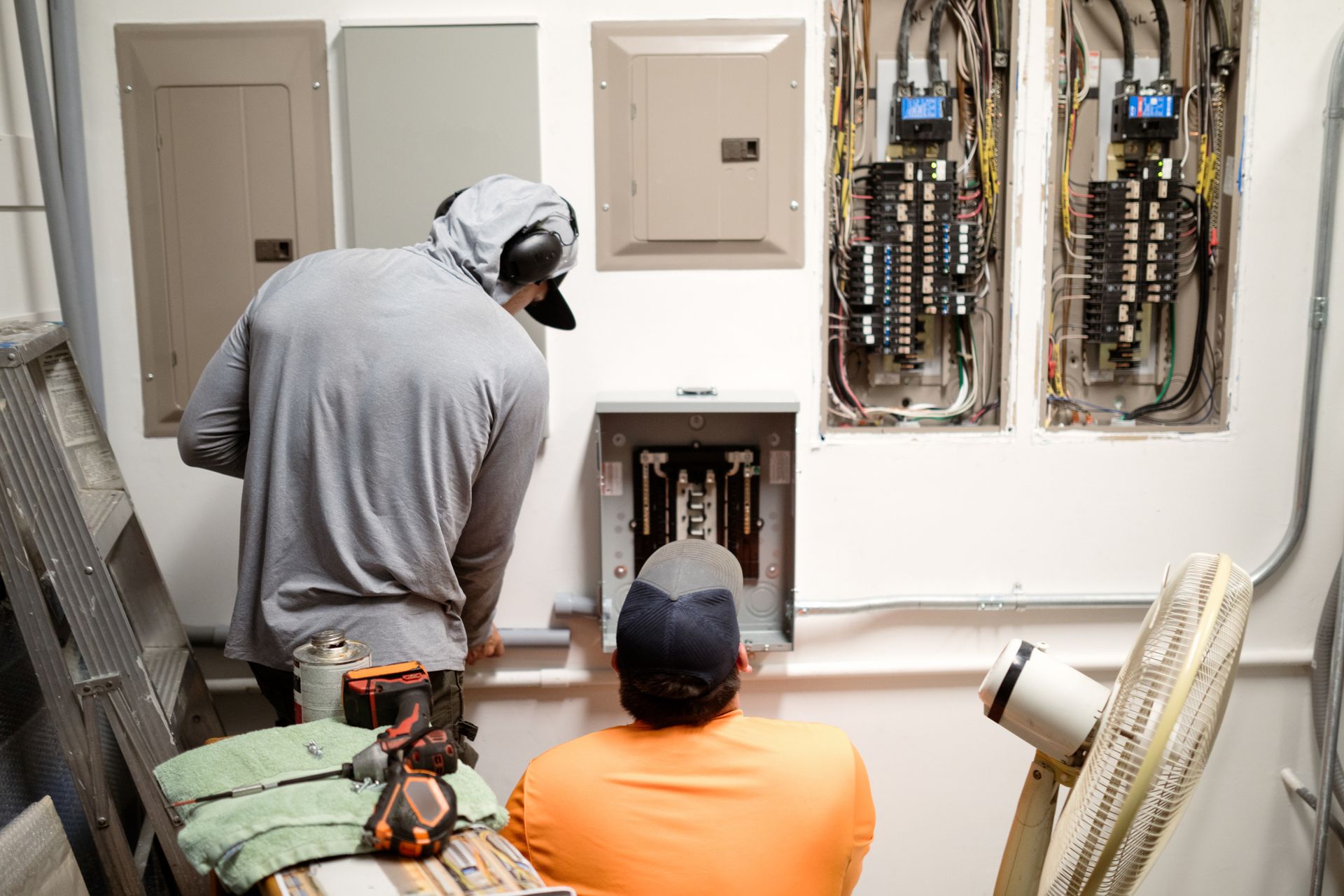A person is working on an electrical box with a screwdriver.