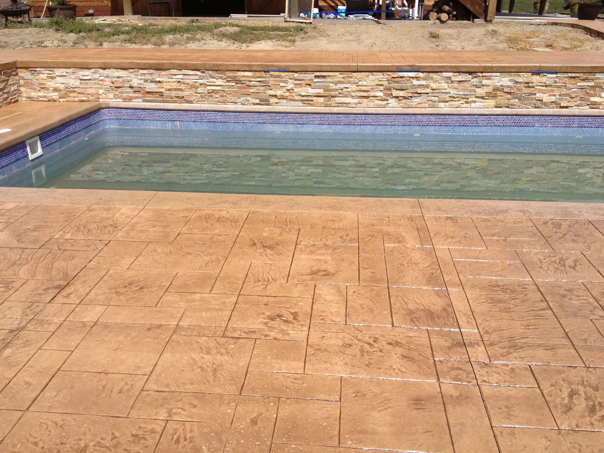 A large swimming pool with a stone wall in the background