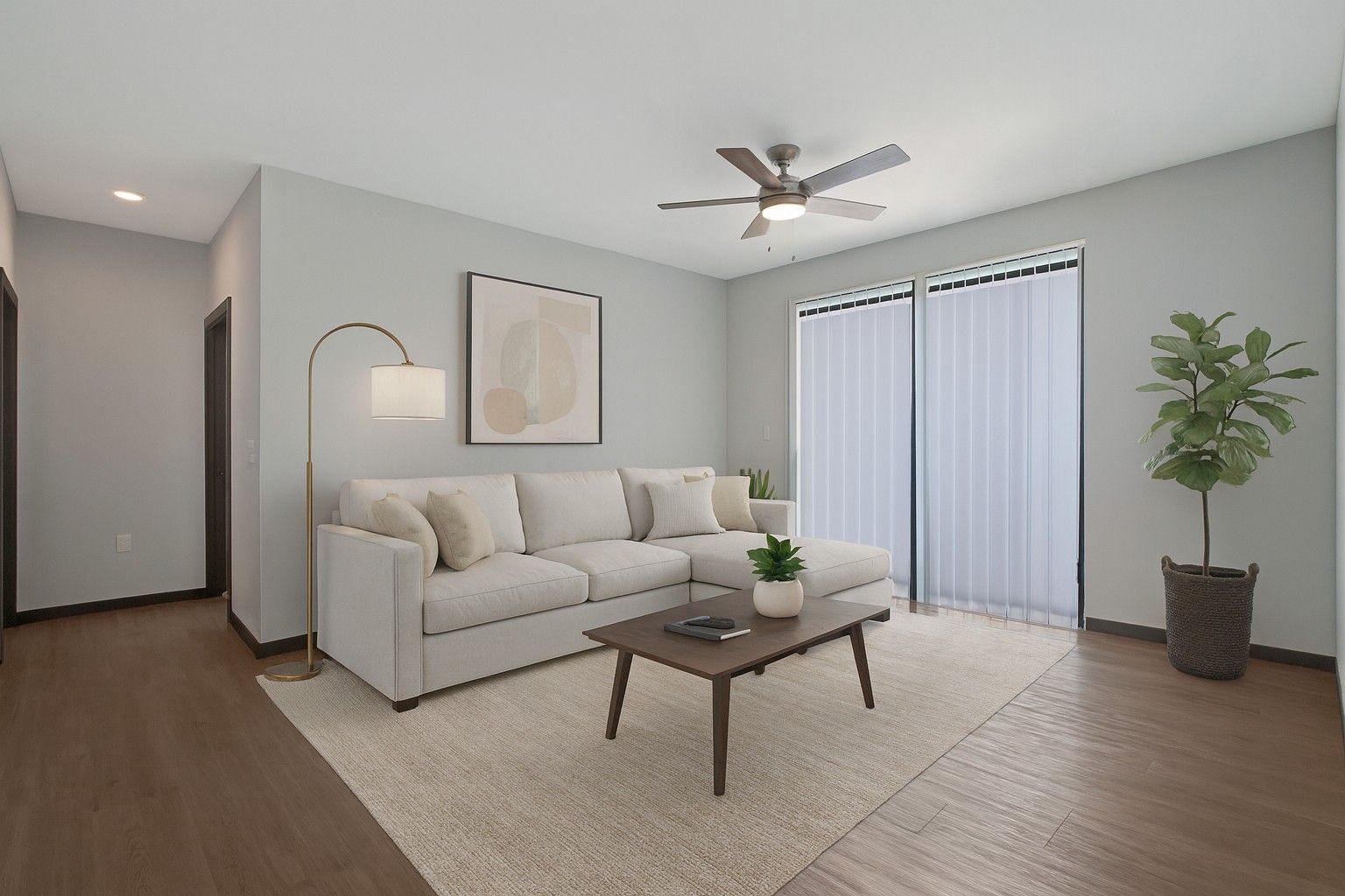 Bright living room with white sofa, coffee table, floor lamp, ceiling fan, and sliding glass doors