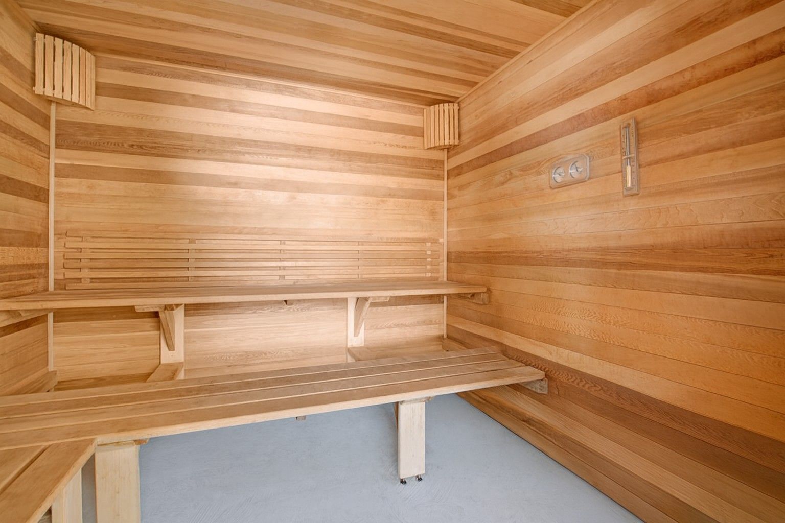 Wood-paneled sauna with bench seating and a heater on the right wall