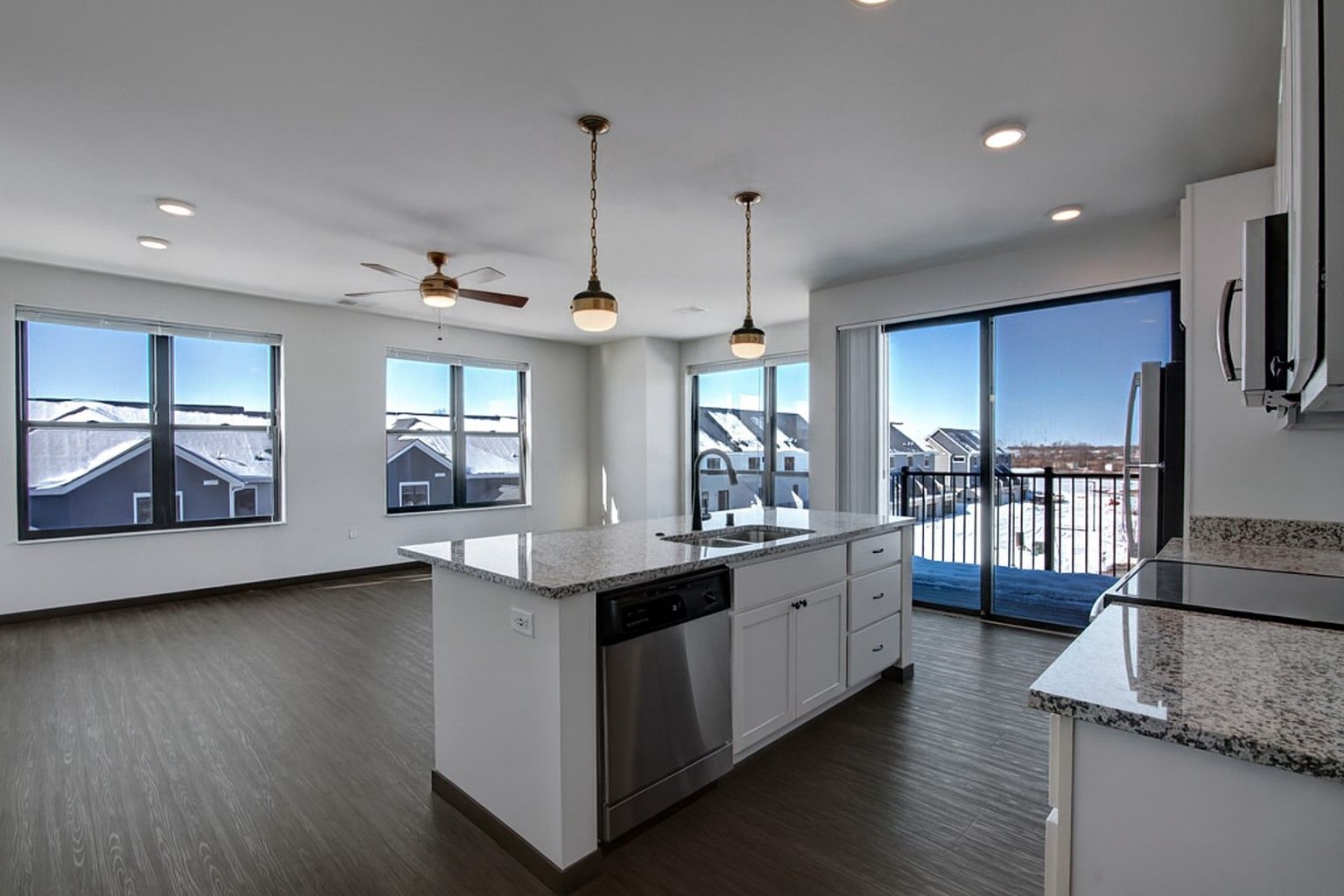 Bright modern kitchen with island, white cabinets, granite counters, and large windows overlooking a snowy view