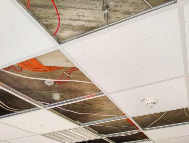 Partially open suspended ceiling with visible wires, acoustic panels, and fixtures