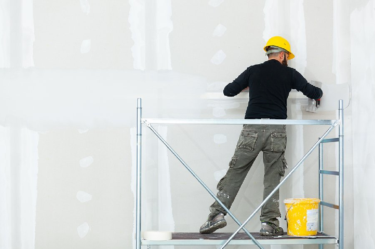 man on scaffolding doing the finishing work on a large drywall job
