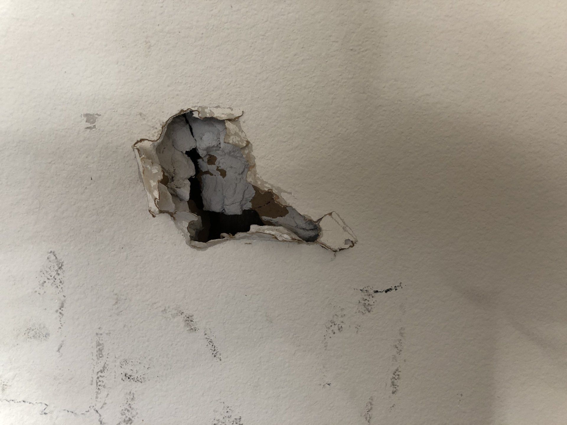 marked up and dirty wall with small hole in drywall