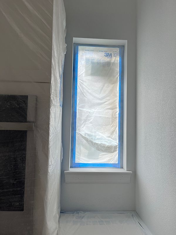 paint job in action, showing a taped window and fireplace inside home