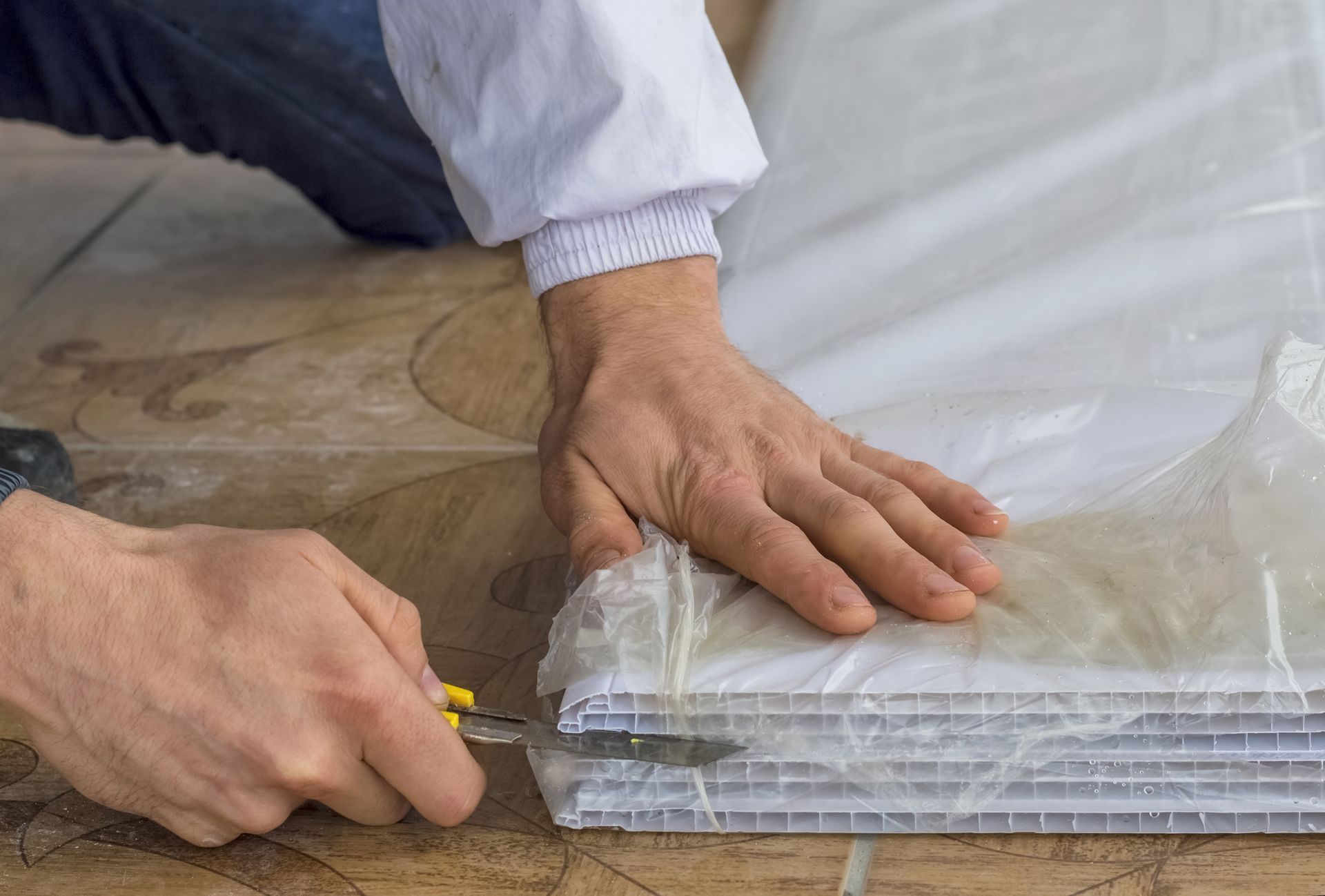 utility knife opening the plastic on a stack of new pvc wall boards