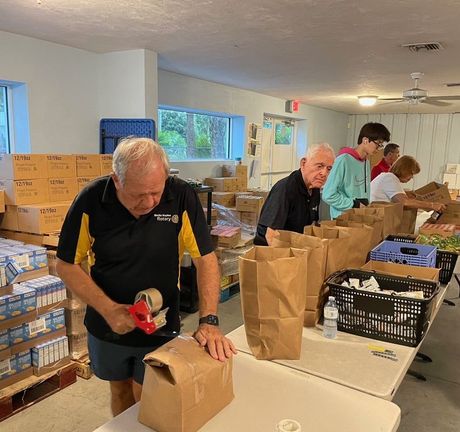 A man and a woman are working on a box of food.
