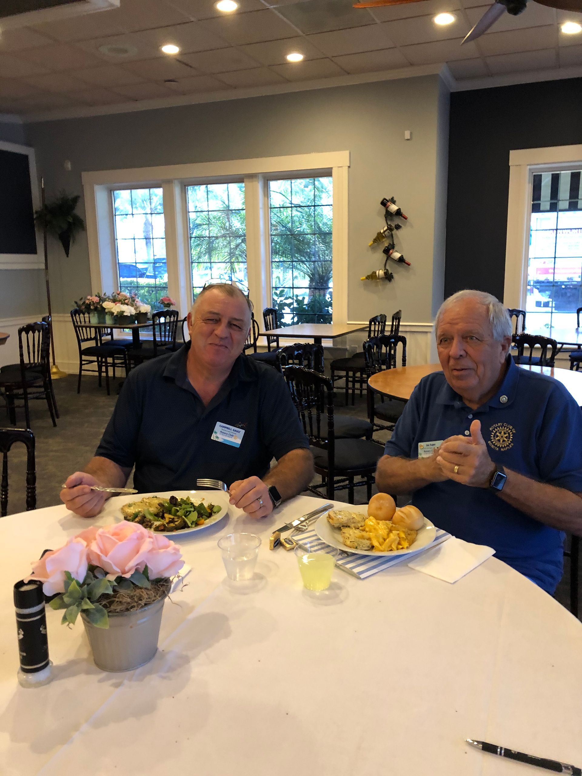 Two men are sitting at a table in a restaurant eating food.