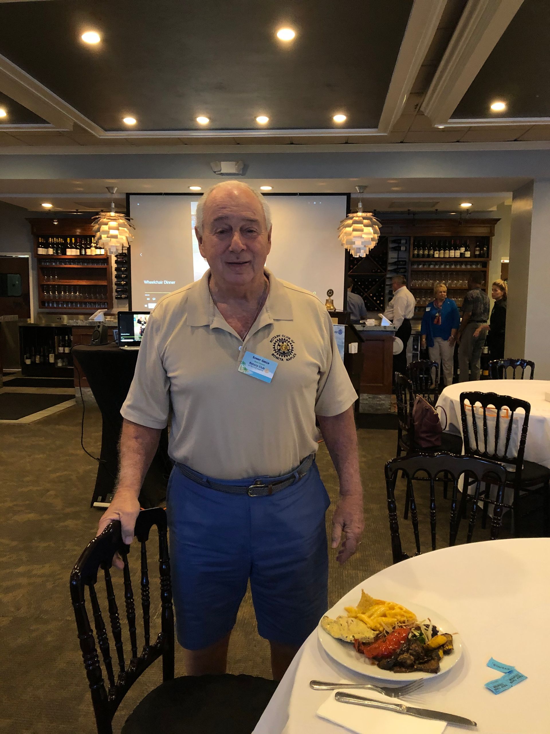 A man is standing next to a table with a plate of food on it.