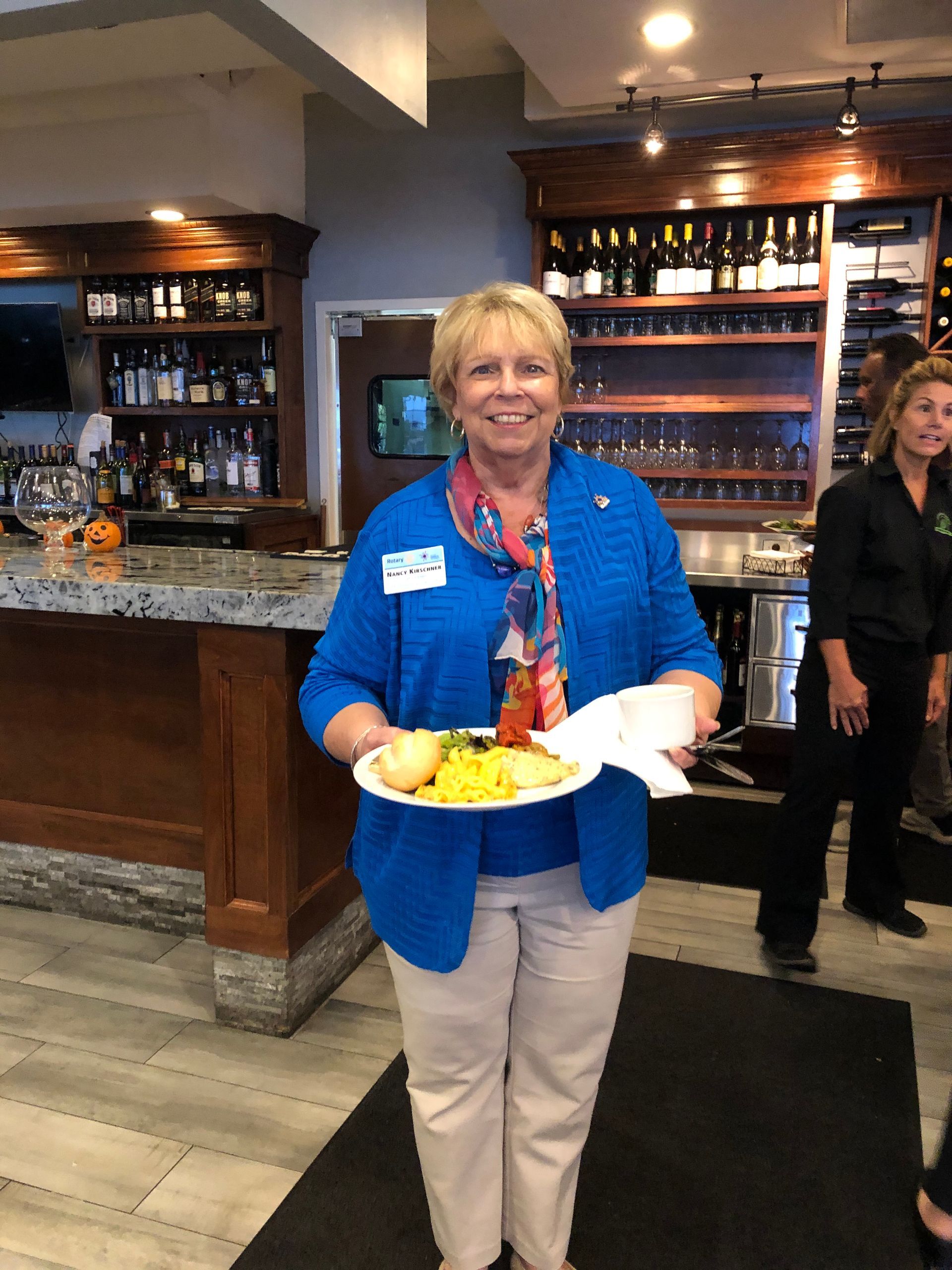 A woman in a blue jacket is holding a plate of food