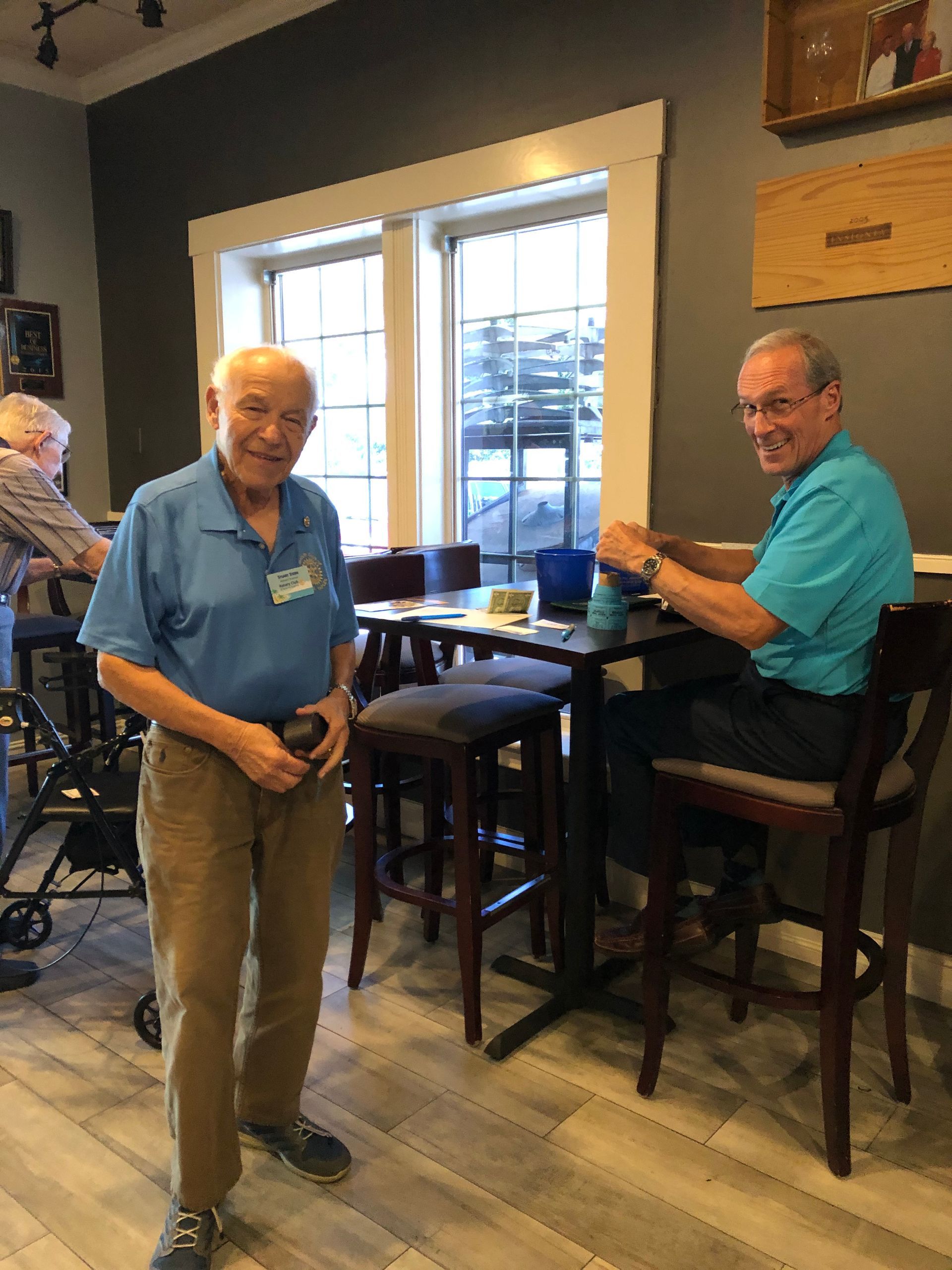 Two men are standing next to each other in a restaurant.