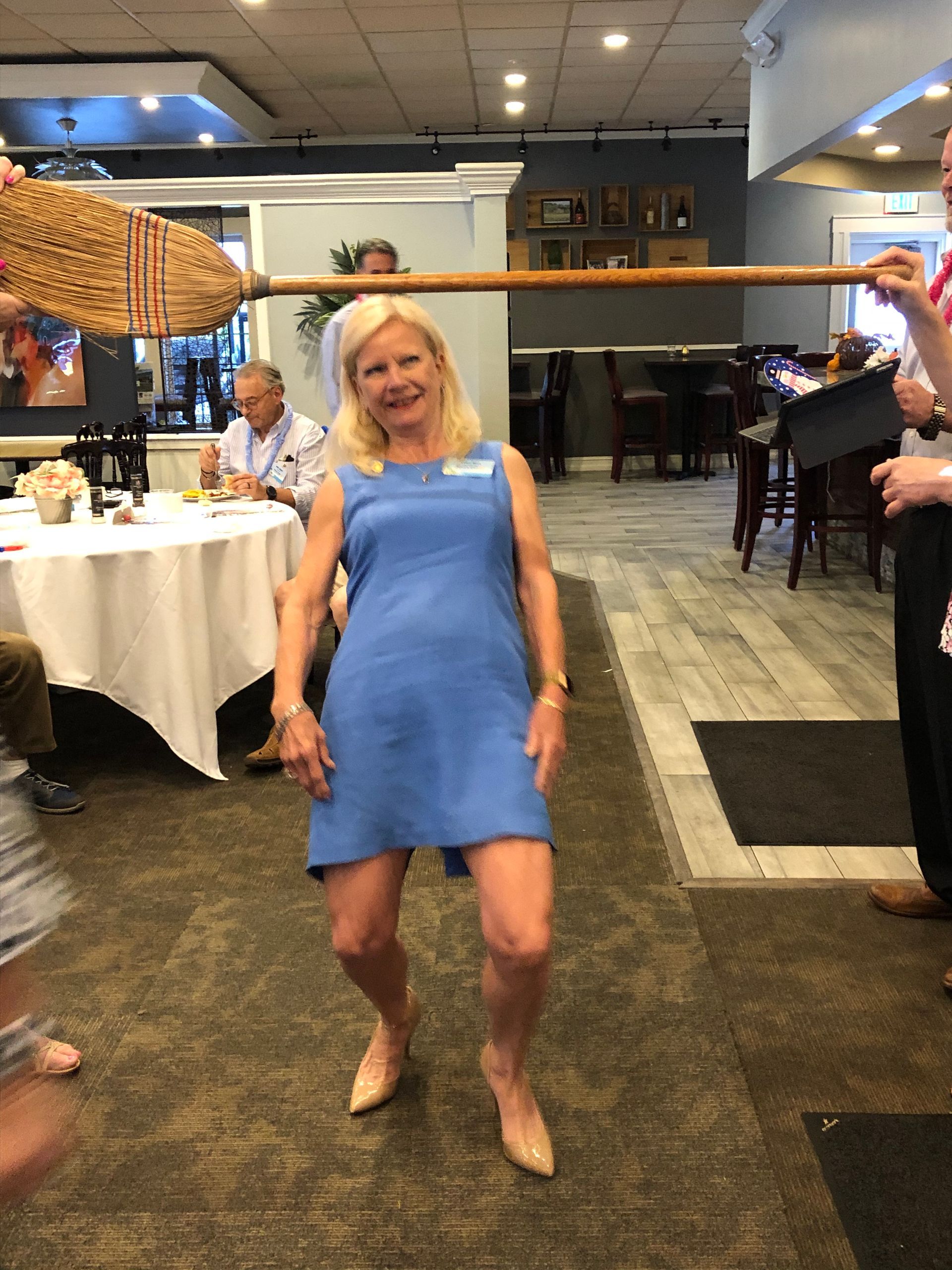 A woman in a blue dress is standing in a room with people.