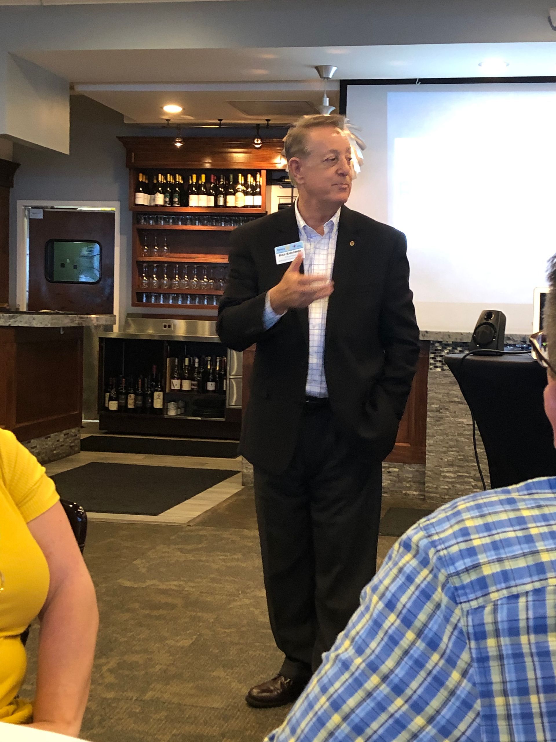 A man in a suit is standing in front of a projector screen