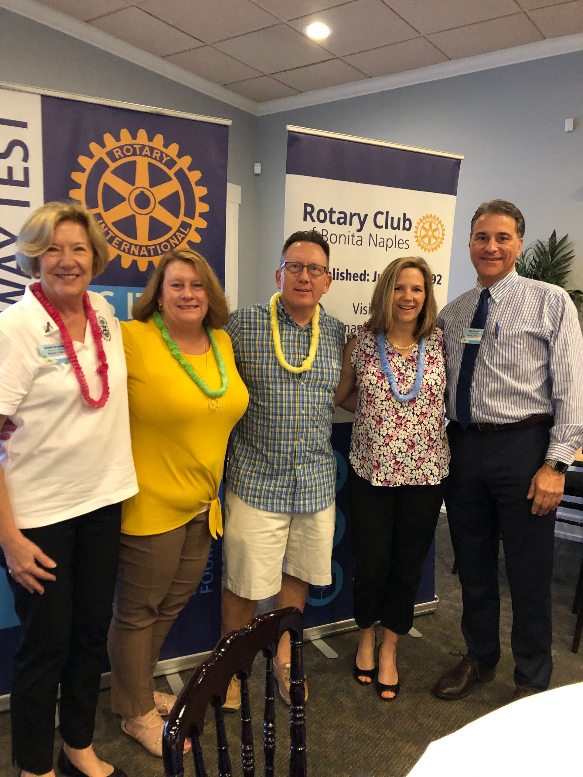 A group of people are posing for a picture in front of a rotary club banner.