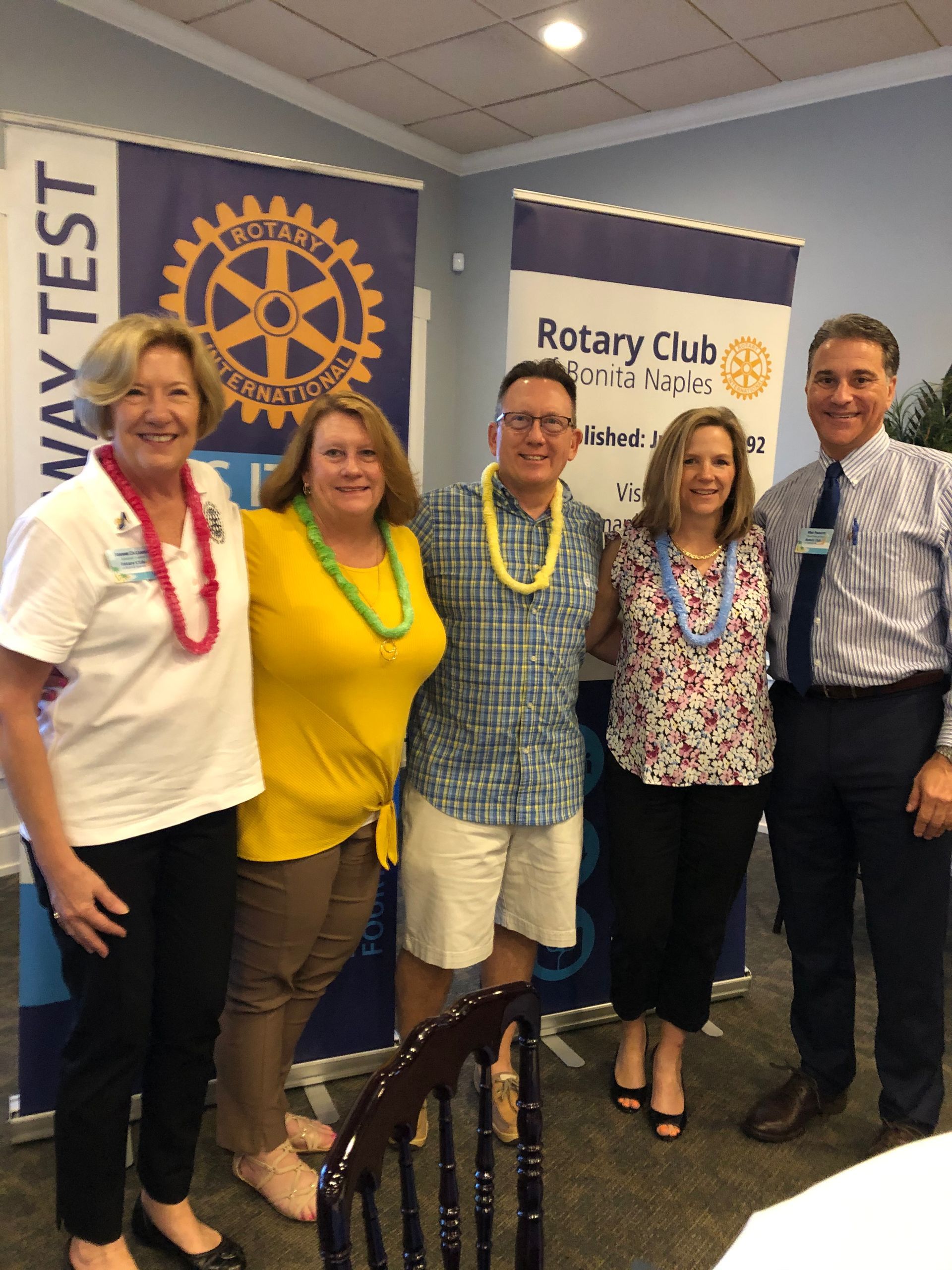 A group of people posing for a picture in front of a rotary club banner