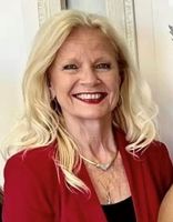 A woman with blonde hair is wearing a red jacket and smiling.