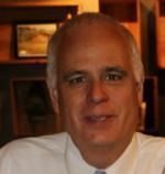 A man in a white shirt and tie is smiling for the camera.