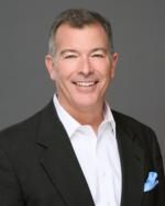 A man in a suit and white shirt is smiling for the camera.