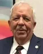 Older man in a suit smiling at the camera.