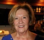 A woman in a blue shirt is smiling for the camera.