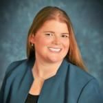 A woman in a blue jacket is smiling for the camera.