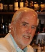 A man with a beard is sitting at a bar.