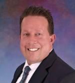 A man in a suit and tie is smiling for the camera.