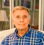 A man in a plaid shirt is sitting in a chair.