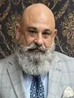 Bald man with a gray beard and mustache, wearing a suit and tie.