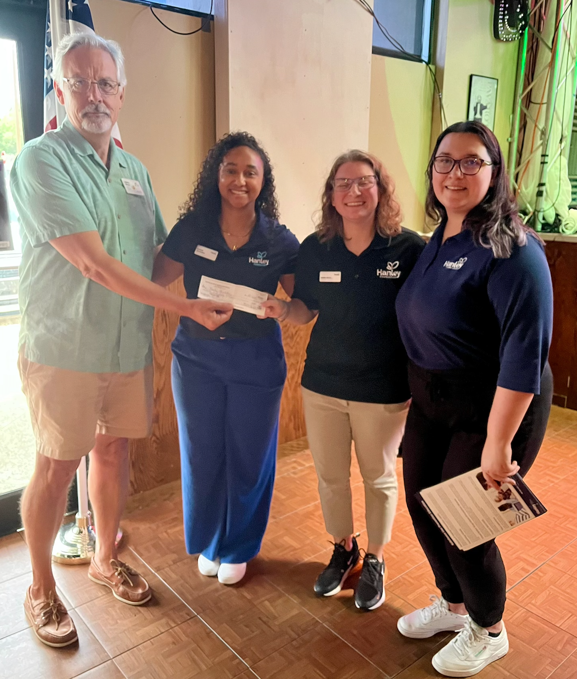 A group of people standing next to each other holding a check.
