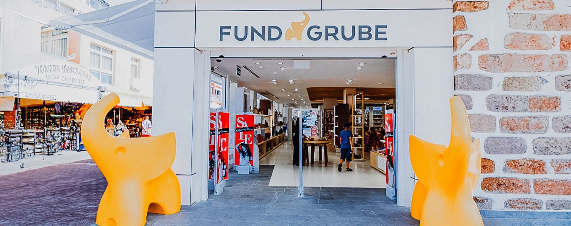 A store front with a yellow elephant statue in front of it.