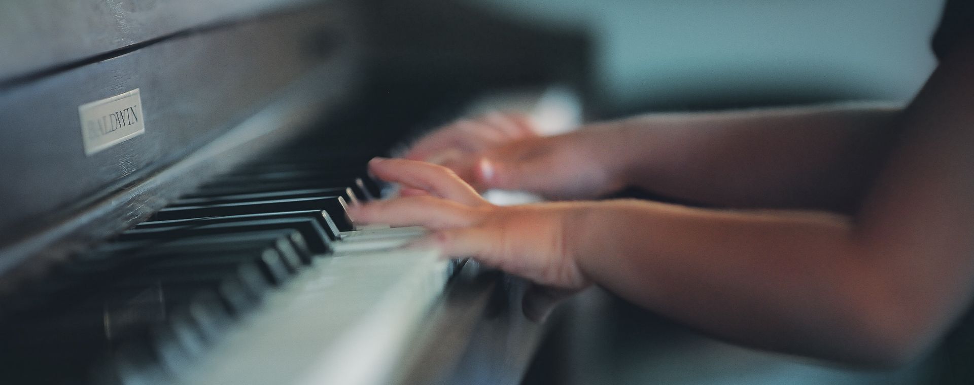 A person is playing a piano with their hands on the keys.