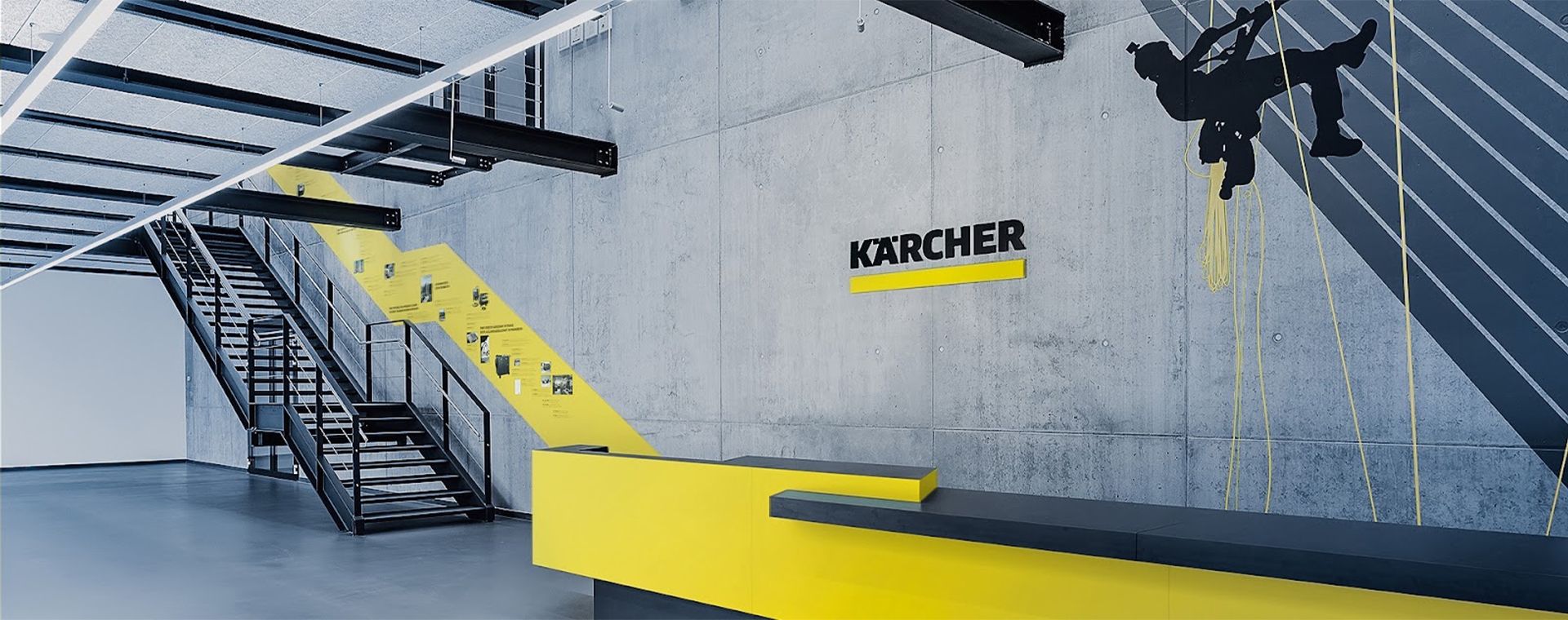 A large room with stairs and a sign that says karcher on the wall.