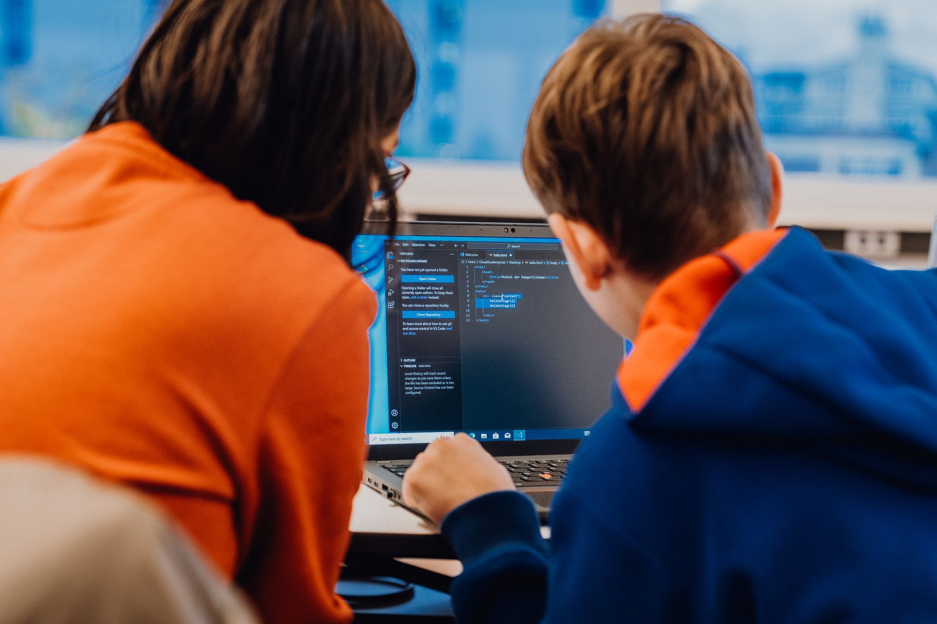 A woman and a boy are looking at a laptop computer.