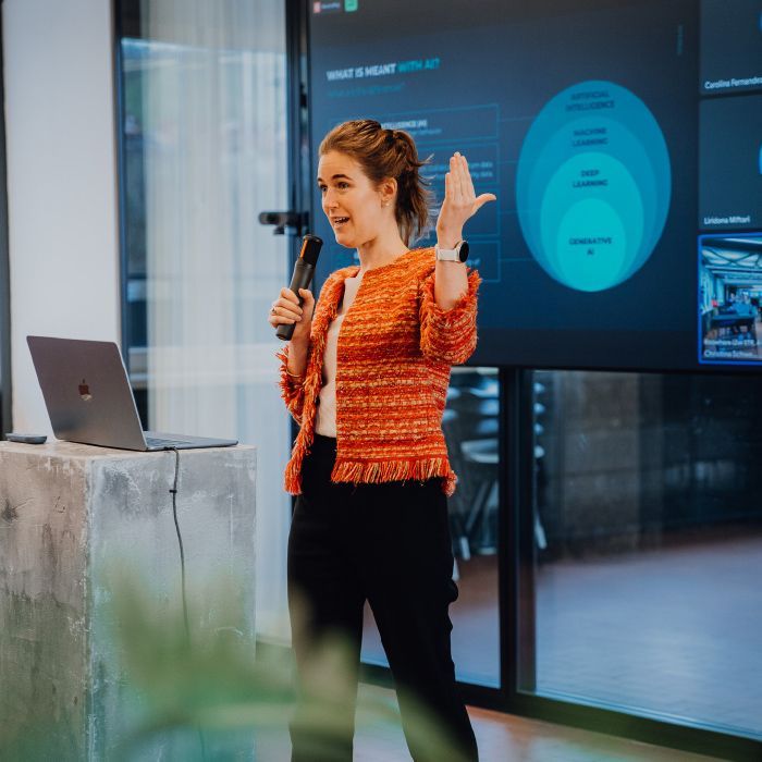 A woman is giving a presentation in front of a large screen
