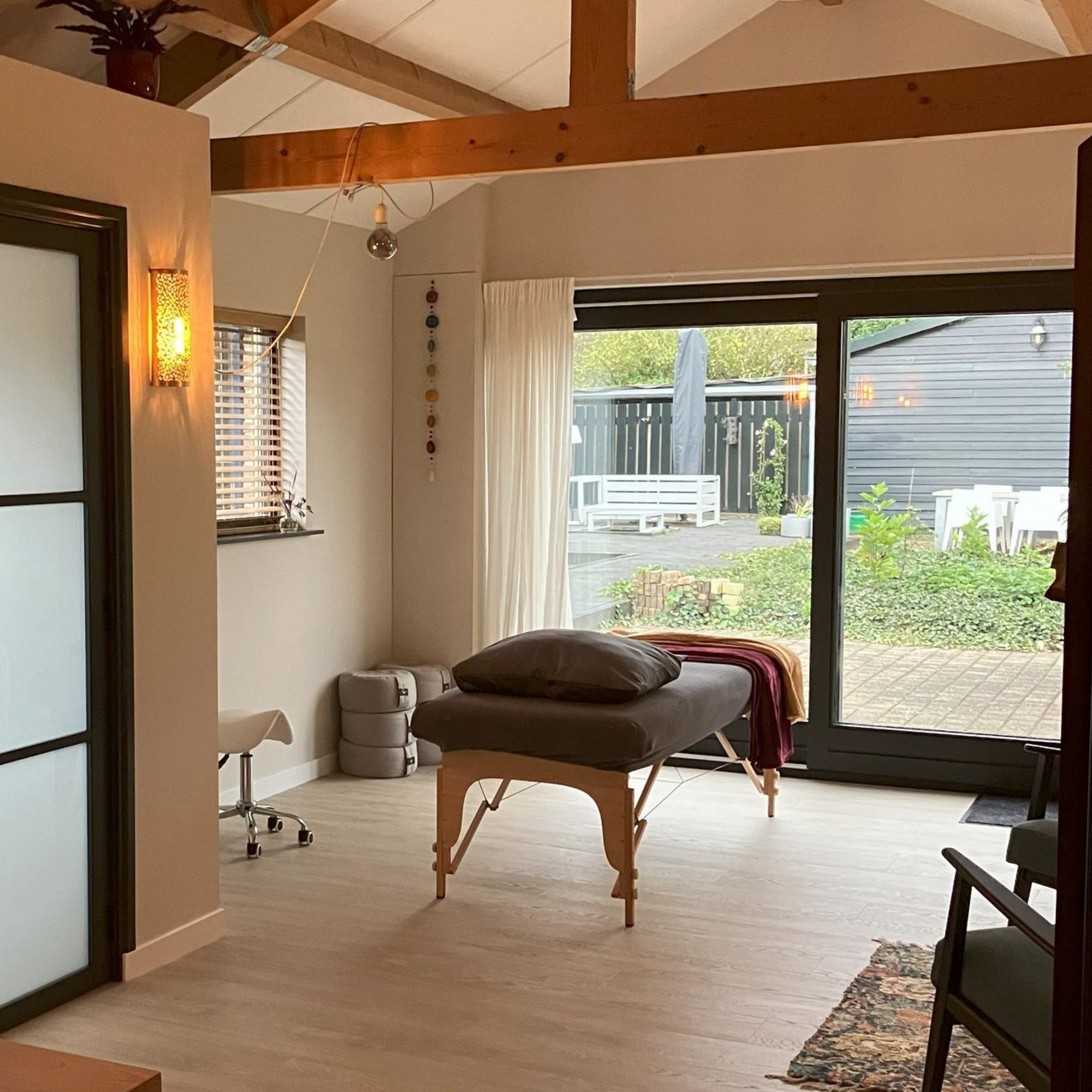 Massageruimte met massagetafel, raam en uitzicht op de tuin.