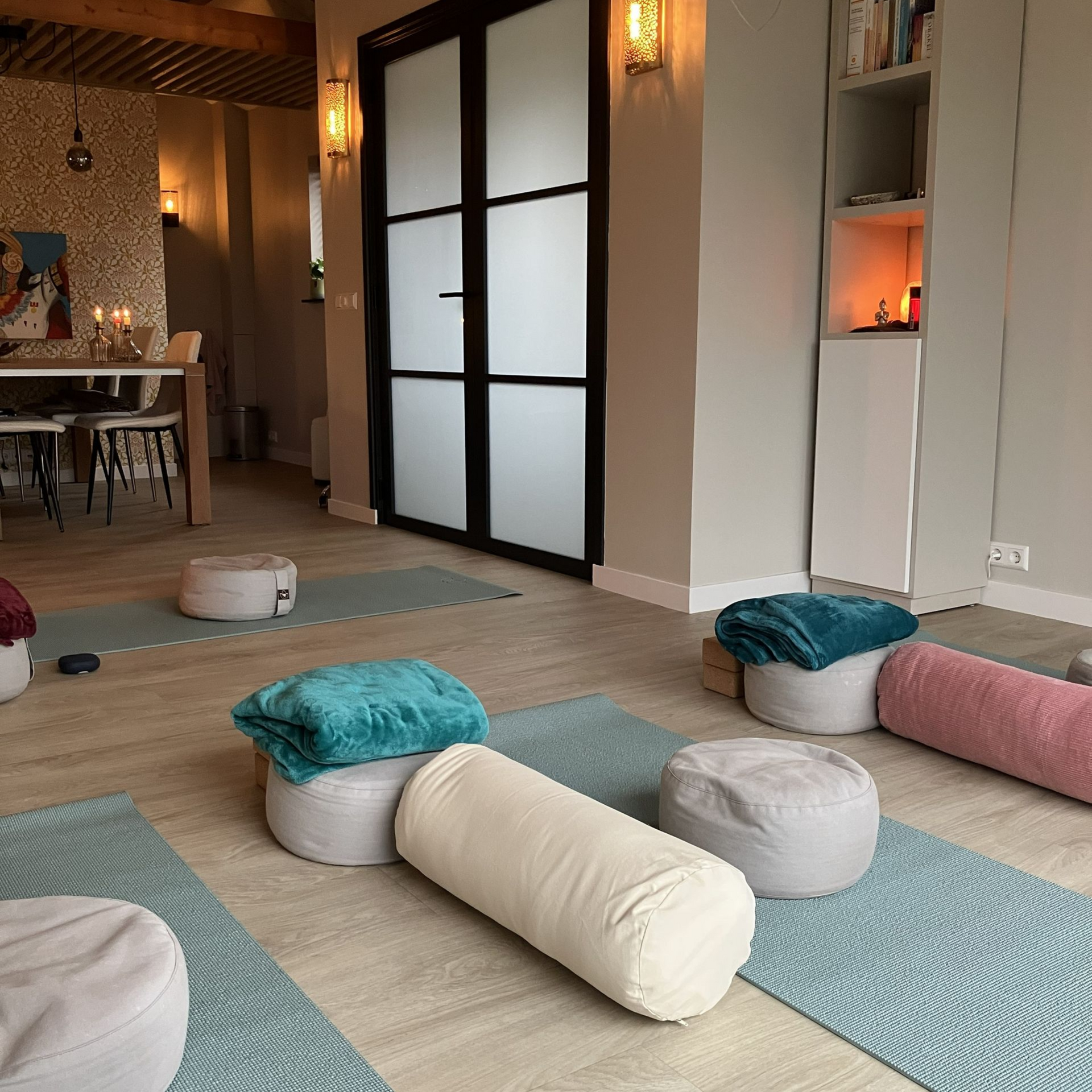 Interieur van een yogastudio met matten, kussens en kussens in een lichte ruimte.